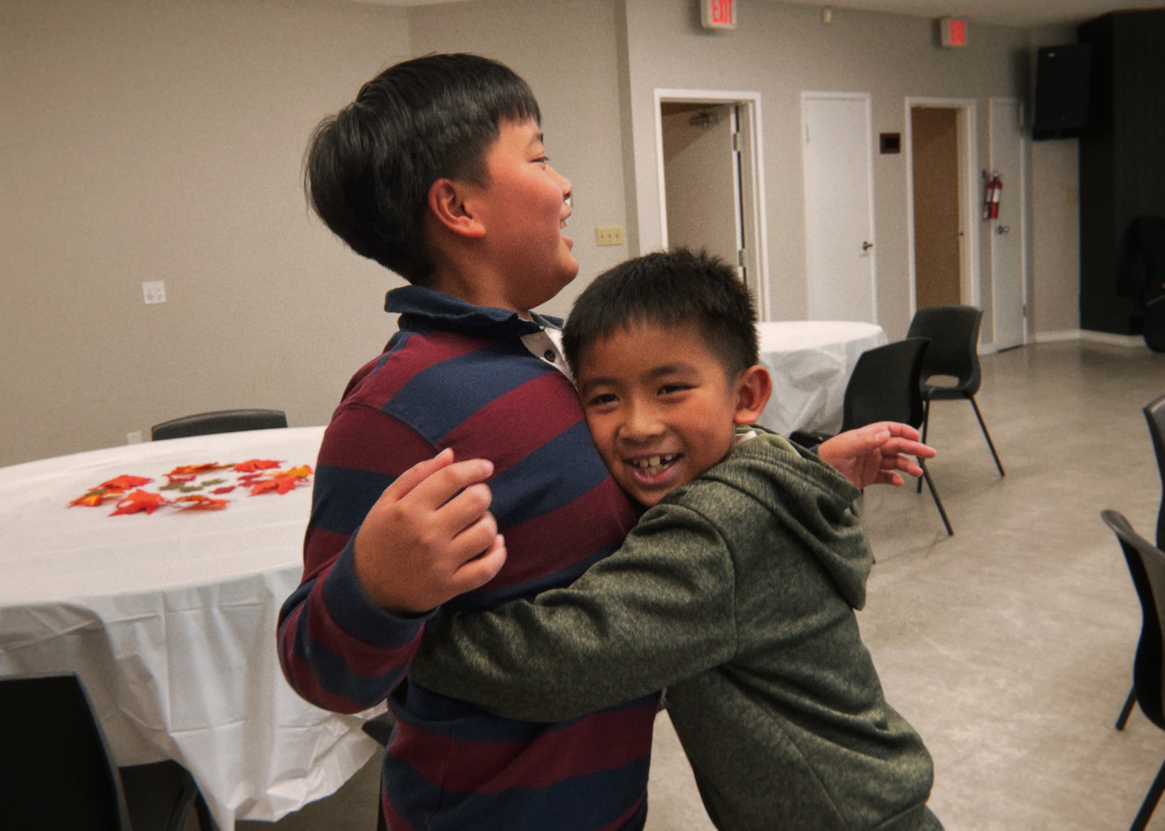 Two children embracing, with the younger child smiling toward the camera